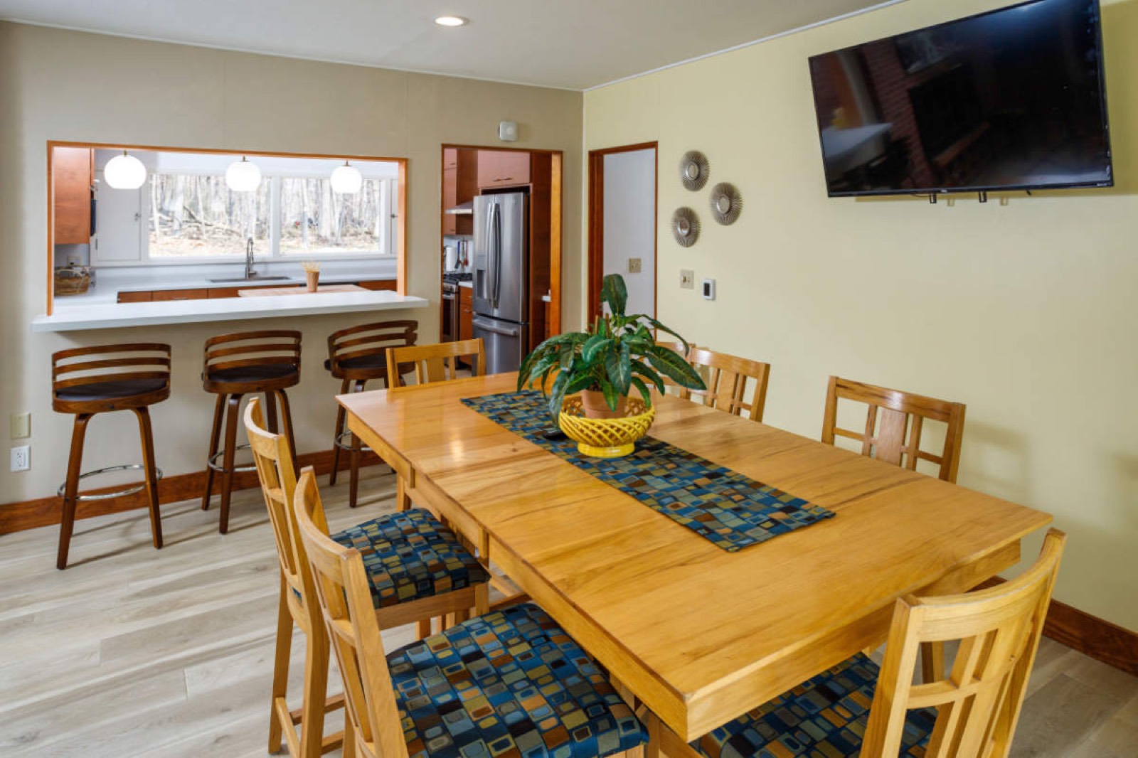 Dining table and living room seating beneath a wall of windows