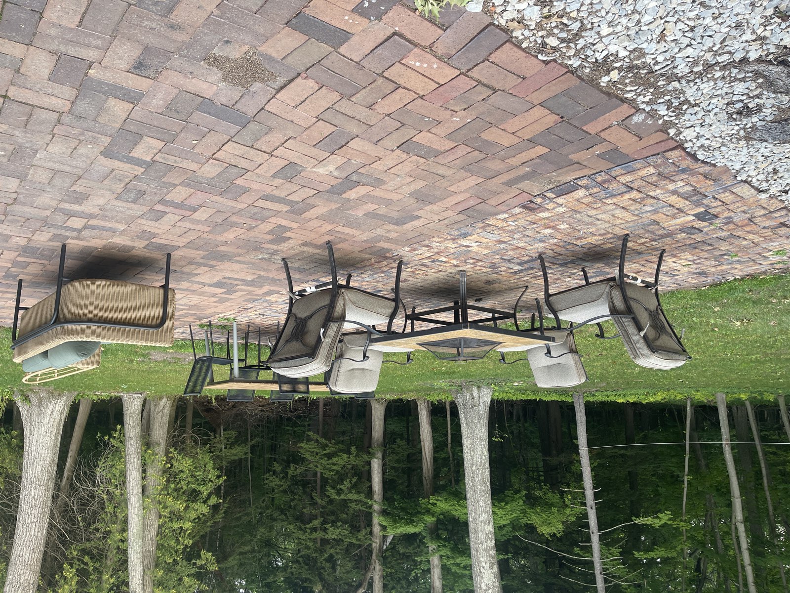 Brick patio with a fire pit and outdoor dining, backed by woods